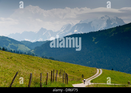 Un cycliste en ordre décroissant le Col des Aravis (1498m) sur la D909 vers Flumet, dans les Alpes françaises, face au Mont Blanc Banque D'Images