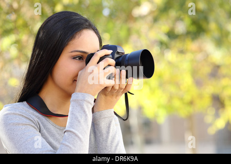 Femme photo photographie d'apprentissage dans un parc heureux avec un arrière-plan flou vert Banque D'Images