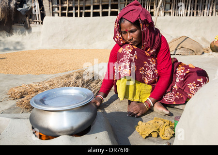 Une femme agriculteur de subsistance la cuisson sur un four en argile traditionnel, à l'aide de tiges de riz comme biocarburant dans les Sunderbans, Ganges, Delta, dans Banque D'Images