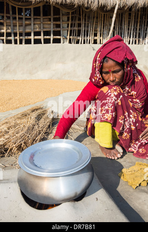 Une femme agriculteur de subsistance la cuisson sur un four en argile traditionnel, à l'aide de tiges de riz comme biocarburant dans les Sunderbans, Ganges, Delta, dans Banque D'Images