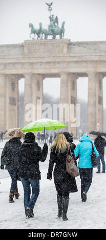 Berlin, Allemagne. Jan 21, 2014. Les touristes à pied en face de la porte de Brandebourg avec parasols comme il neige à Berlin, Allemagne, 21 janvier 2014. Photo : HANNIBAL/dpa/Alamy Live News Banque D'Images