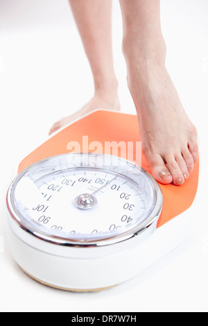 Une femme se mesure sur l'échelle de pesage Banque D'Images
