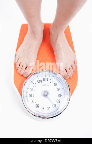 Une femme se mesure sur l'échelle de pesage Banque D'Images