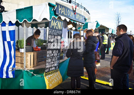 Marché de London food à Canary Wharf. La préparation et la vente du vendeur la nourriture grecque Halloumi attaches pour les clients d'attente. uk market stall. Banque D'Images