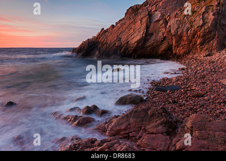 Rochers sur la plage et les falaises au coucher du soleil le long de la côte rocheuse, à Josefinelust / Kullaberg Kullen, Skåne / Scania, Suède Banque D'Images