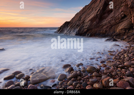 Rochers sur la plage et les falaises au coucher du soleil le long de la côte rocheuse, à Josefinelust / Kullaberg Kullen, Skåne / Scania, Suède Banque D'Images