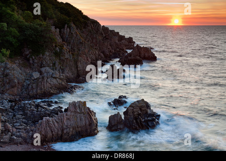 Rochers sur la plage et les falaises au coucher du soleil le long de la côte rocheuse, à Josefinelust / Kullaberg Kullen, Skåne / Scania, Suède Banque D'Images