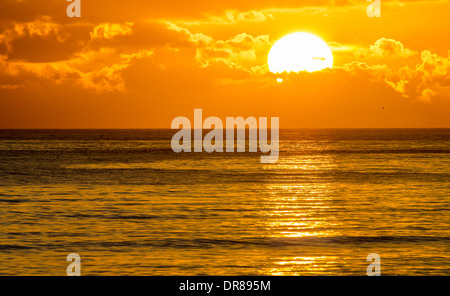 Coucher de soleil sur la mer en partie derrière les nuages. Banque D'Images