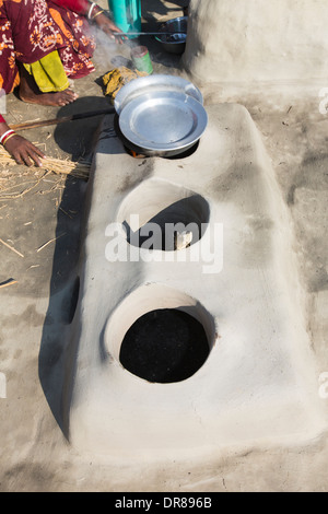 Une femme agriculteur de subsistance la cuisson sur un four en argile traditionnel, à l'aide de tiges de riz comme biocarburant dans les Sunderbans, Ganges, Delta, dans Banque D'Images