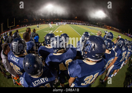 Joueurs de football de l'école secondaire regarder un jeu de nuit dans les coulisses à San Juan Capistrano, CA. Banque D'Images