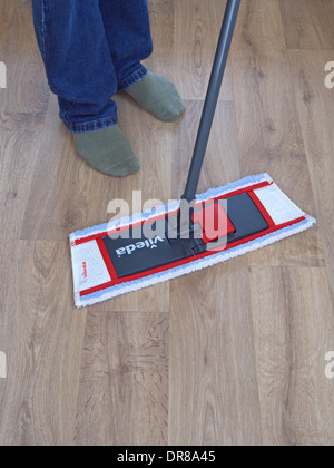 L'homme à l'aide d'une vadrouille Vileda sur un plancher de vinyle Effet Bois, MODÈLE BRITANNIQUE PUBLIÉ Banque D'Images