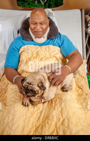 Un patient de l'hôpital dans le sud de la Californie en étreignant un Pug dog confort apporté par un bénévole. Communiqué de modèle Banque D'Images