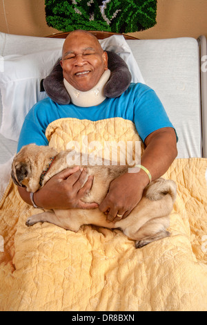 Un patient de l'hôpital dans le sud de la Californie en étreignant un Pug dog confort apporté par un bénévole. Communiqué de modèle Banque D'Images