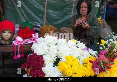 Un vendeur de chapeaux de laine à tricoter entre les ventes au marché aux fleurs, Chiang Mai, Thaïlande Banque D'Images