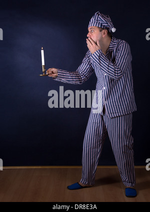 L'homme effrayé avec bougie en pyjama. Banque D'Images