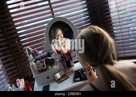 Un 15 16 17 ans adolescente maquiller à son reflet dans la chambre miroir avant de sortir d'une partie, UK Banque D'Images