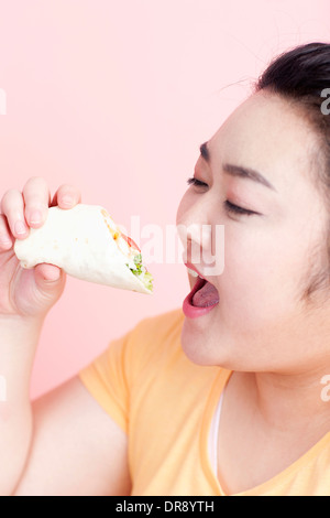 Une femme rondelette à propos de manger sandwich wrap Banque D'Images