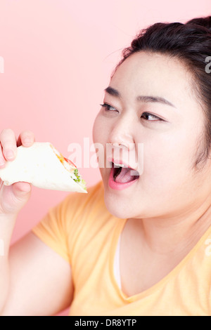 Une femme rondelette à propos de manger sandwich wrap Banque D'Images