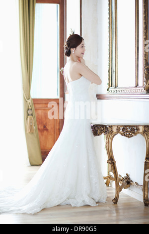 Une femme en robe de mariage standing in front of mirror Banque D'Images