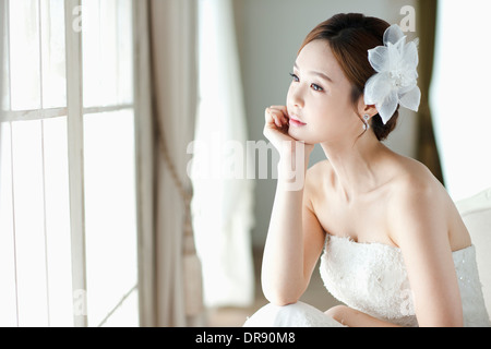 Une femme en robe de mariage en regardant par la fenêtre Banque D'Images