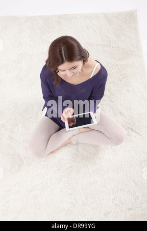 Une femme assise sur un tapis à l'aide de Tablet PC Banque D'Images