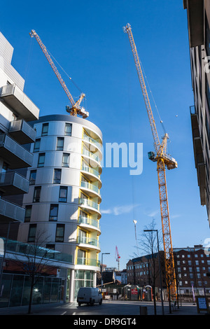 Groupe de grues sur un chantier de construction de nouvelles maisons dans le centre de Reading, Berkshire, England, GB, au Royaume-Uni. Banque D'Images