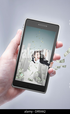 Une main tenant un téléphone portable avec une femme d'intérieur avec de l'argent Banque D'Images