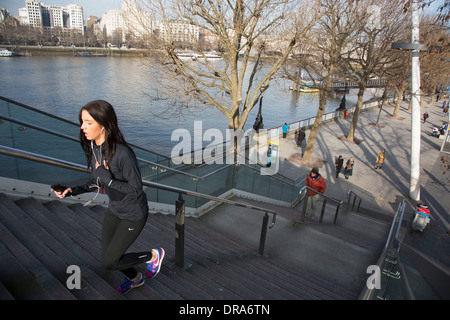 Les coureurs midi passé grâce à la lumière d'hiver sur la rivière passerelle sur la Southbank. La Banque du Sud est un important quartier des spectacles, c'est promenade Riverside occupé avec les visiteurs et les touristes. Londres, Royaume-Uni. Banque D'Images