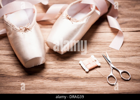 Chaussures de ballet avec des ciseaux et les cordes sur un sol en bois Banque D'Images