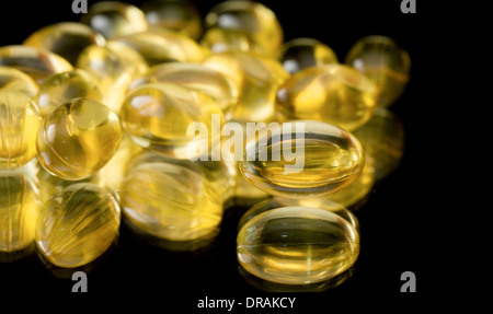 Les gélules d'huile de foie de morue sur un fond en miroir noir Banque D'Images