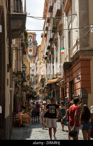 Les touristes se promener le long des rues secondaires dans la ville de Sorrente, avec la tour en arrière-plan. Banque D'Images