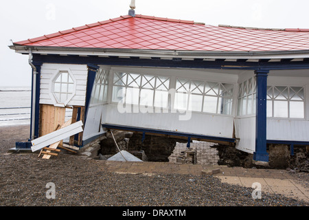 Après une semaine de fortes marées, les ondes de tempête et des vents violents, de la promenade du front de mer d'Aberystwyth au Pays de Galles a été dévastée, avec des millions d'€ de dommages. Le crsahing vagues coup de poing à un grand trou dans le mur de la mer s'est effondré et l'emblématique d'Aberystwyth, promenade victorienne d'abris, qui a résisté pendant plus de 100 ans. Cette photo a été prise le mercredi 8 janvier 2014, le jour où le conseil a commencé à essayer et effacer les milliers de tonnes de gravats plage front de mer au large de la route. Banque D'Images