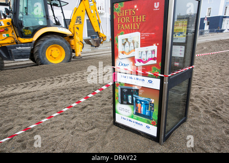 Après une semaine de fortes marées, les ondes de tempête et des vents violents, de la promenade du front de mer d'Aberystwyth au Pays de Galles a été dévastée, avec des millions d'€ de dommages. Le fracas des vagues de poing à un grand trou dans le mur de la mer s'est effondré et l'emblématique d'Aberystwyth, promenade victorienne d'abris, qui a résisté pendant plus de 100 ans. Cette photo a été prise le mercredi 8 janvier 2014, le jour où le conseil a commencé à essayer et effacer les milliers de tonnes de gravats plage front de mer au large de la route. Banque D'Images