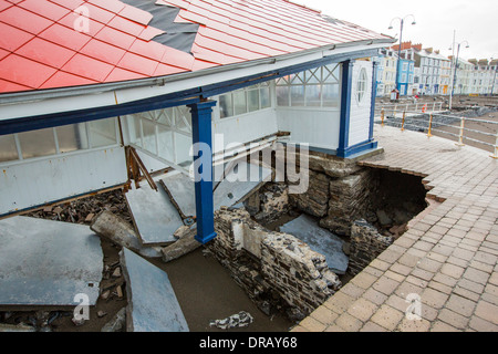 Après une semaine de fortes marées, les ondes de tempête et des vents violents, de la promenade du front de mer d'Aberystwyth au Pays de Galles a été dévastée, avec des millions d'€ de dommages. Le crsahing vagues coup de poing à un grand trou dans le mur de la mer s'est effondré et l'emblématique d'Aberystwyth, promenade victorienne d'abris, qui a résisté pendant plus de 100 ans. Cette photo a été prise le mercredi 8 janvier 2014, le jour où le conseil a commencé à essayer et effacer les milliers de tonnes de gravats plage front de mer au large de la route. Banque D'Images