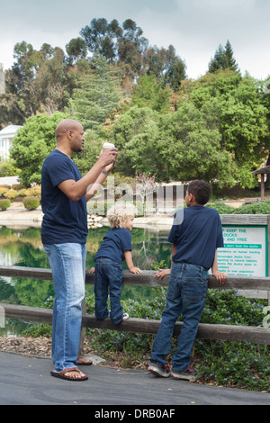 Père avec enfants leaning on wooden fence à Menlo Park Banque D'Images