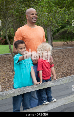 Heureux père avec enfants à la recherche à vue depuis une clôture en bois Banque D'Images