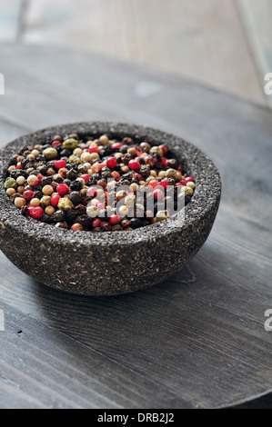 Mélanger le poivre dans un bol de pierre sur fond de bois. Banque D'Images