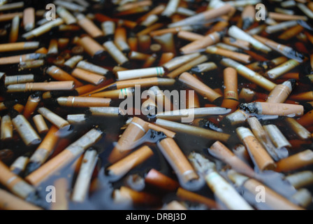 Fag butts flotter dans un récipient/cendrier géant, à l'extérieur de Queen Alexandra Hospital, Portsmouth, Hampshire, Angleterre. Banque D'Images