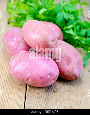 Tas de pommes de terre rouges, avec le persil sur un fond en bois Banque D'Images