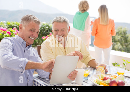 Senior men using digital tablet table patio Banque D'Images