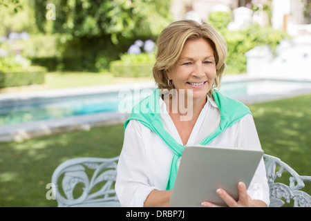 Senior woman using digital tablet in backyard Banque D'Images