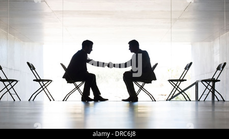 Businessmen shaking hands in office Banque D'Images