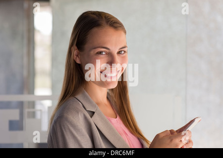 Businesswoman using cell phone in office Banque D'Images