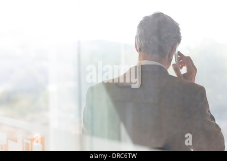 Businessman talking on cell phone in office Banque D'Images