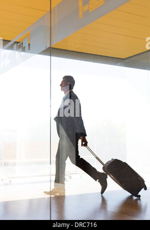 Businessman pulling suitcase dans le corridor de l'aéroport Banque D'Images