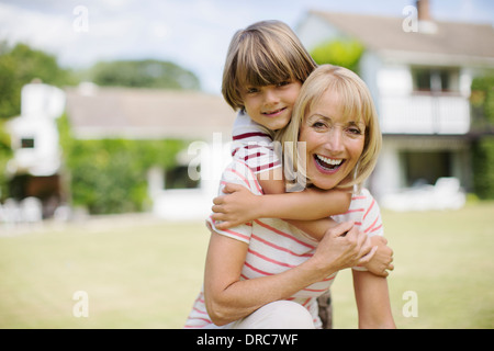 Grand-mère et petit-fils hugging in backyard Banque D'Images