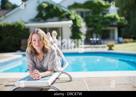 Woman laying on diving board at poolside Banque D'Images