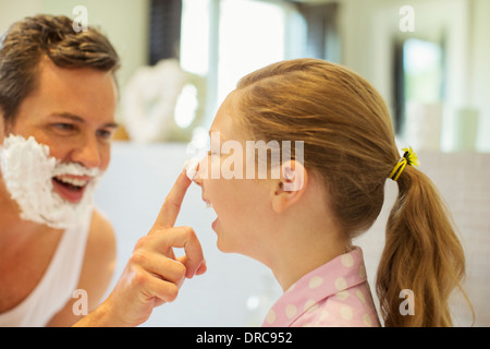 Père et fille jouer avec la crème à raser dans la salle de bains Banque D'Images