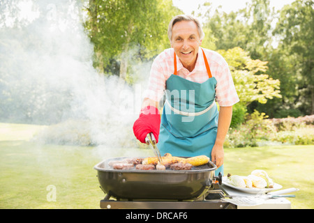 Man grilling food sur barbecue in backyard Banque D'Images