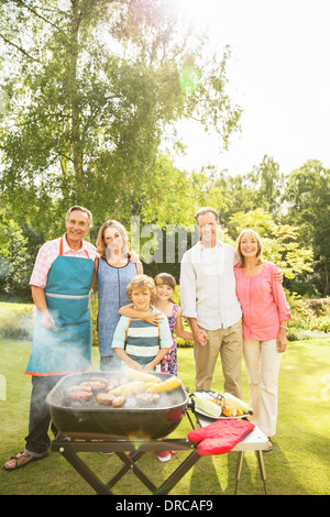 Multi-generation family standing at barbecue in backyard Banque D'Images